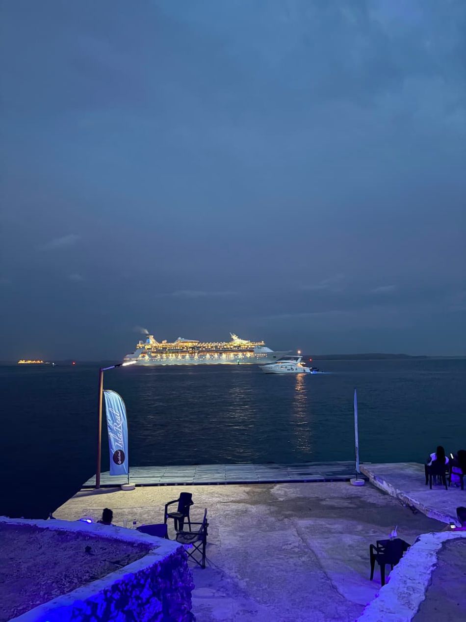 Muelle de la isla al atardecer, con un crucero iluminado al fondo