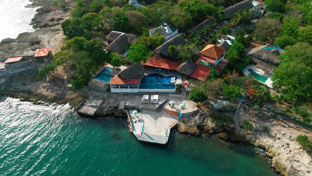 Vista aérea de la Isla Open Mind, con piscina, cabañas y muelle sobre el mar